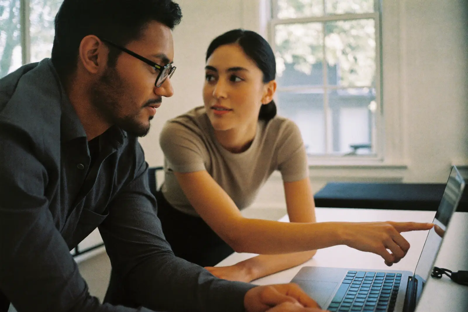 Two agency professionals review accounts together over a laptop in a bright meeting room