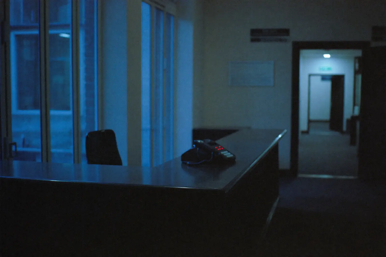 An empty law firm reception desk after hours in cool evening light, the phone unattended