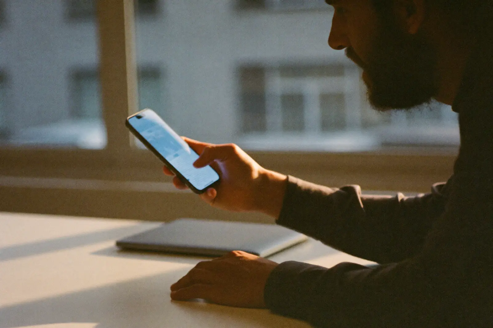 A business owner at his desk reads a flagged conversation on his phone, about to step in and reply